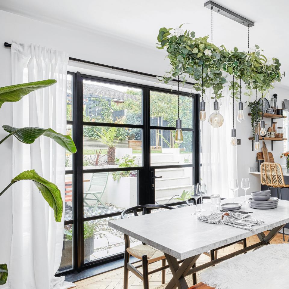 dining area with French doors, white table with bench seating, and foliage on pendant light