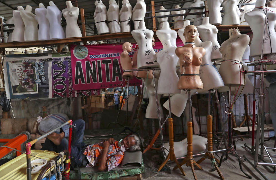 In this Thursday, April 30, 2020, photo, a man naps among mannequins at Tanah Abang textile market that is closed due to the new coronavirus outbreak in Jakarta, Indonesia. May Day usually brings both protest rallies and celebrations rallies marking international Labor Day. This year it's a bitter reminder of how much has been lost for the millions left idle or thrown out of work due to the coronavirus pandemic. Garment workers in Asia are among the hardest hit as orders dry up and shutdowns leave factories shuttered. (AP Photo/Tatan Syuflana)