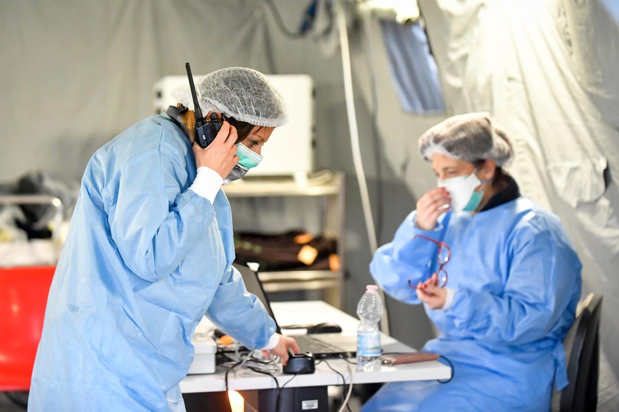 In this Saturday, Feb. 29, 2020 file photo, paramedics work in a tent that was set up outside the hospital of Cremona, northern Italy.