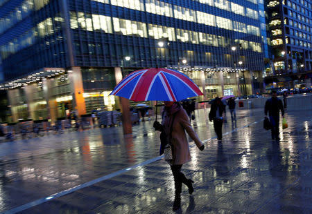 FILE PHOTO: Workers walk in the rain at the Canary Wharf business district in London, Britain November 11, 2013. REUTERS/Eddie Keogh/File Photo