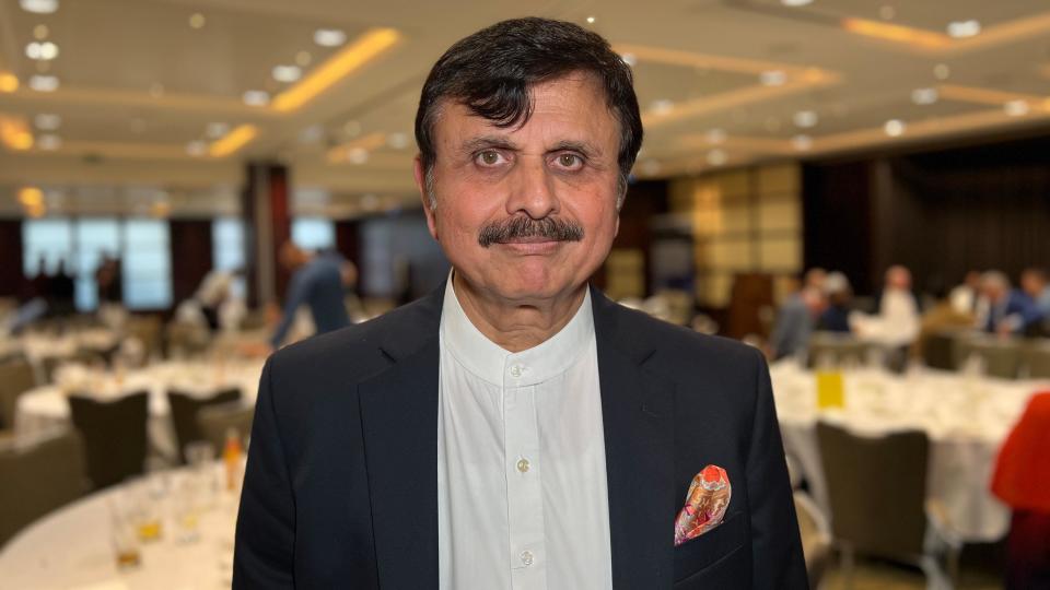 Dr Sarfaraz Jamali looks at the camera in front of chairs and tables where people have been eating their food during the Eid celebrations