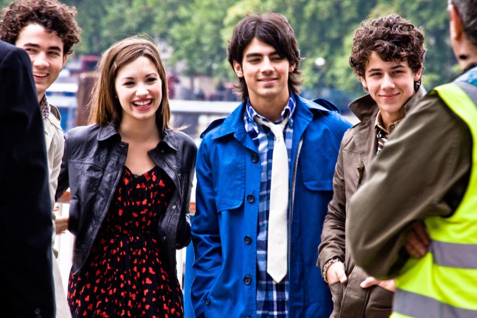 An older photo of the Jonas brothers smiling with Demi Lovato