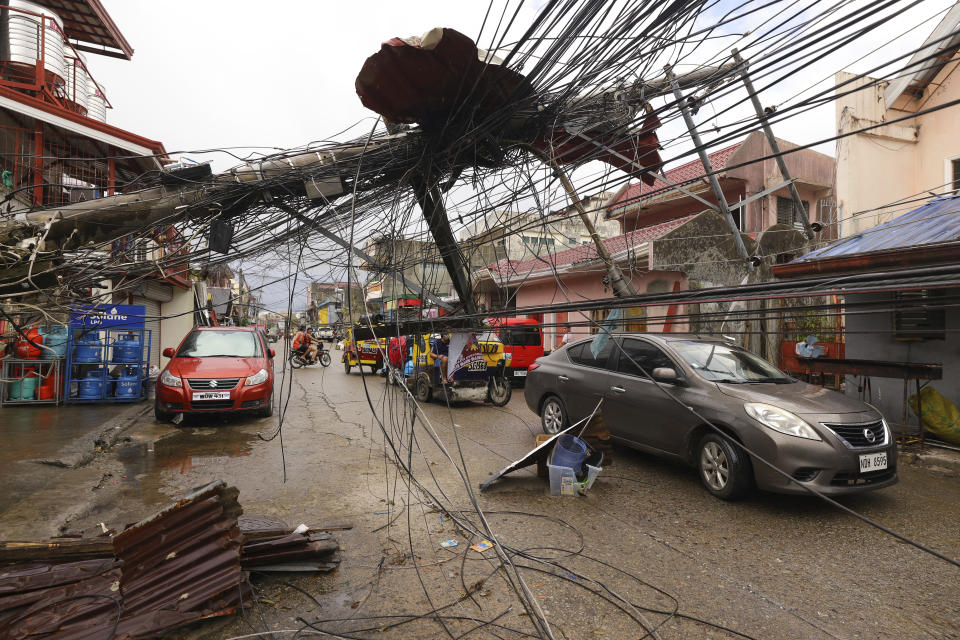 CAPTION CHANGES PHOTO SOURCE In this photo provided by Greenpeace, cars pass by a toppled electrical post due to Typhoon Rai in Surigao city, Surigao del Norte, southern Philippines as power supply remain down on Sunday Dec. 19, 2021. The death toll in the strongest typhoon to batter the Philippines this year continues to rise and the governor of an island province especially hard-hit by Typhoon Rai said there may be even greater devastation that has yet to be reported. (Jilson Tiu/Greenpeace via AP)