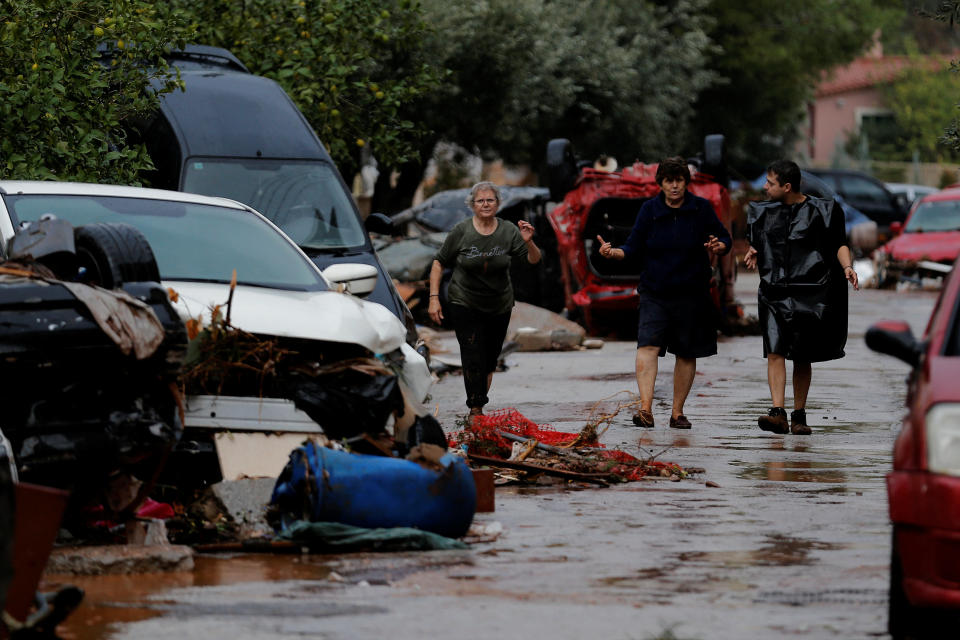 Locals walk next to destroyed cars following heavy rainfall. (Photo: Alkis Konstantinidis/Reuters)