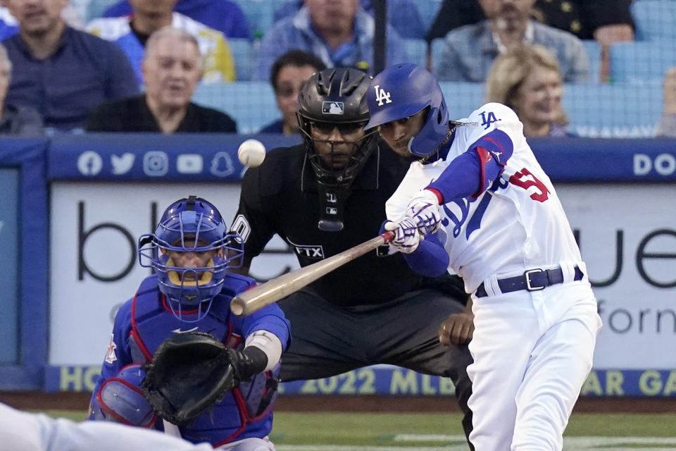 Los Angeles Dodgers' Mookie Betts, right, hits a solo home run as Chicago Cubs catcher Yan Gomes, left, and home plate umpire Jose Navas watch during the first inning of a baseball game Thursday, July 7, 2022, in Los Angeles. (AP Photo/Mark J. Terrill)