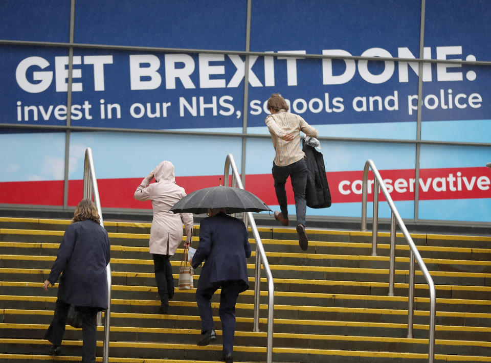 Delegates arrive in heavy rain at the Conservative Party Conference in Manchester, England, Tuesday, Oct. 1, 2019. Britain's Prime Minister Boris Johnson said Tuesday that his government prepared at last to make firm proposals for a new divorce deal with the European Union. Britain is due to leave the 28-nation bloc at the end of this month, and EU leaders are growing impatient with the U.K.'s failure to set out detailed plans for maintaining an open border between Northern Ireland and Ireland — the key sticking point to a deal. (AP Photo/Frank Augstein)