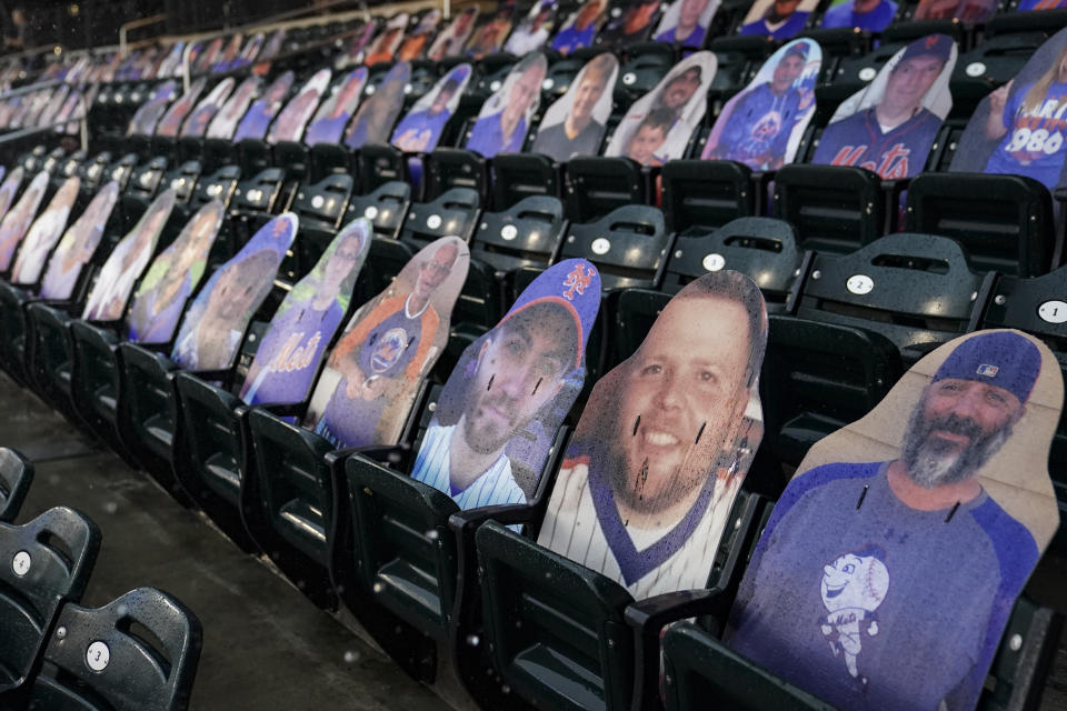 Rain falls onto cardboard cutouts of fans in the stands during a delay in the third inning of the first baseball game of a doubleheader between the New York Mets and the Miami Marlins, Tuesday, Aug. 25, 2020, in New York. (AP Photo/John Minchillo)