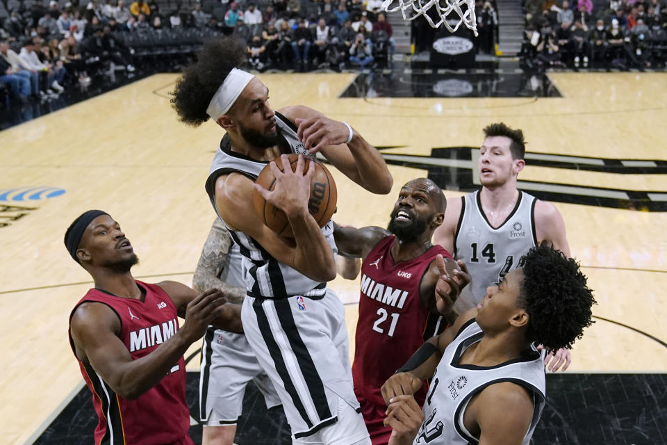 San Antonio Spurs guard Derrick White, center, grabs a rebound over Miami Heat center Dewayne Dedmon (21) during the first half of an NBA basketball game Thursday, Feb. 3, 2022, in San Antonio. (AP Photo/Eric Gay)