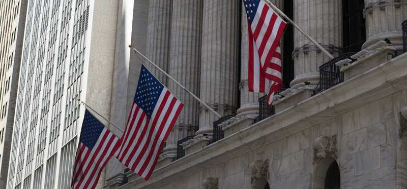 American flags hang on the outside of a stone building in the city.