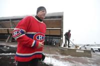 A man, wearing a Montreal Canadiens jersey, jogs past a Jean Beliveau statue, in front of an arena named after Beliveau in Longueuil December 3, 2014. REUTERS/Christinne Muschi
