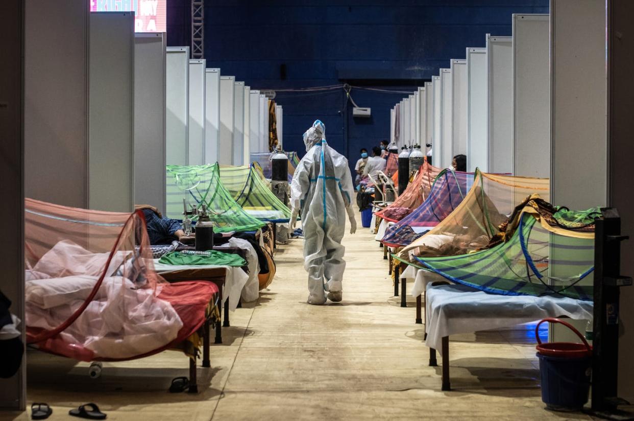 <span class="caption">A COVID-19 surge has pushed hospitals in India beyond their capacity. A stadium in New Delhi was being used as a makeshift ward on May 2, 2021.</span> <span class="attribution"><a class="link " href="https://www.gettyimages.com/detail/news-photo/medical-worker-in-ppe-observes-patients-who-have-been-news-photo/1315876823" rel="nofollow noopener" target="_blank" data-ylk="slk:Getty Images;elm:context_link;itc:0;sec:content-canvas">Getty Images</a></span>