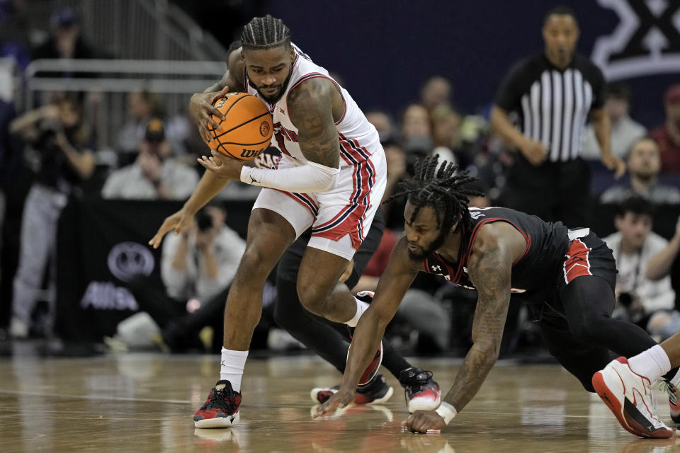 Houston guard Jamal Shead, left, avoids a steal by Texas Tech guard Joe Toussaint, left, during the first half of an NCAA college basketball game in the semifinal round of the Big 12 Conference tournament, Friday, March 15, 2024, in Kansas City, Mo. (AP Photo/Charlie Riedel)