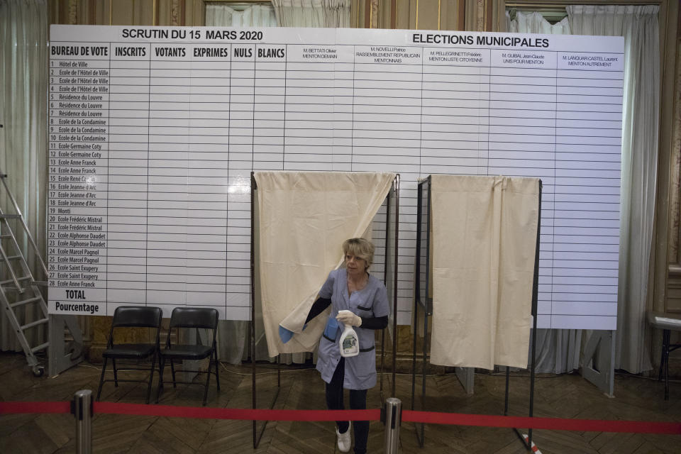 A worker disinfects a voting booth to protect from the new coronavirus at a voting center in the French-Italian border city of Menton, southern France, Sunday, March 15, 2020. For most people, the new coronavirus causes only mild or moderate symptoms. For some it can cause more severe illness. France pressed ahead with plans for nationwide municipal elections on Sunday but ordered special measures to keep people at a safe distance and to sanitize surfaces. (AP Photo/Daniel Cole)