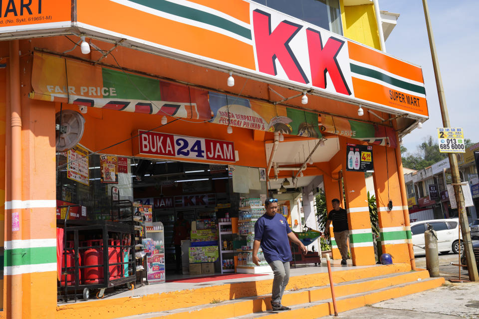 A customer walk out from KK Mart convenience store in Puchong area on the outskirts of of Kuala Lumpur, Malaysia, Tuesday, March 26, 2024. The owner of a Malaysian convenience store chain was charged Tuesday with deliberately wounding the religious feelings of others after socks with the word "Allah" were found sold in some outlets. (AP Photo/Vincent Thian)