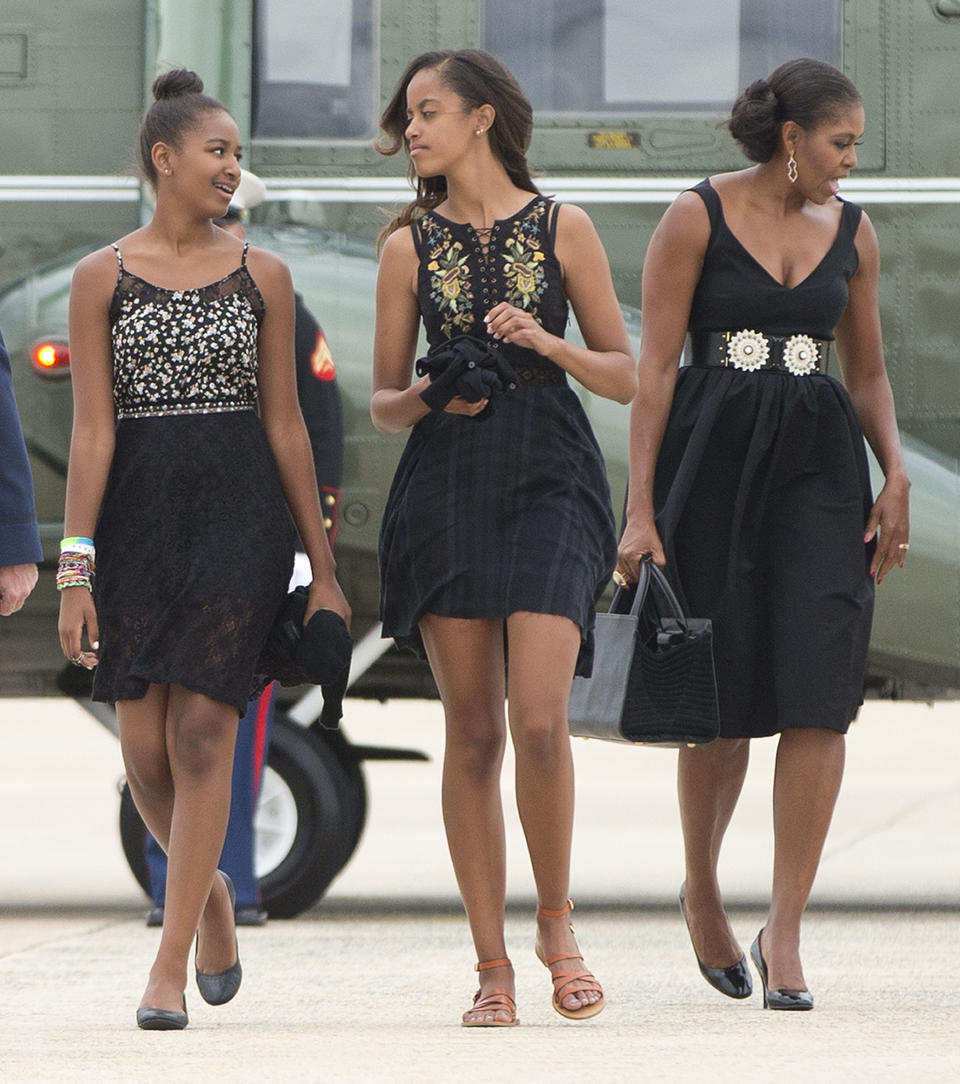 First lady Michelle Obama and her daughters Sasha and Malia walk across the tarmac before boarding Air Force One prior to their departure from Andrews Air Force Base, Saturday, Aug. 30, 2014. The first family traveled to Westchester County, N.Y., to attend the wedding ceremony of White House chef Sam Kass and MSNBC host Alex Wagner.