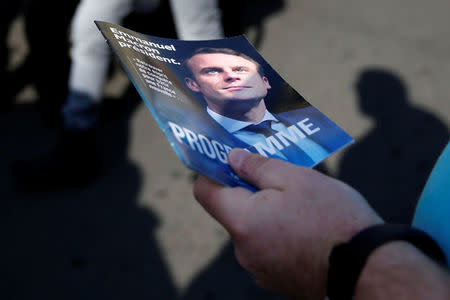 A supporter of Emmanuel Macron, head of the political movement En Marche !, or Onwards !, and candidate for the 2017 French presidential election, distributes political leaflets at a local market in Henin-Beaumont, France, April 7, 2017. REUTERS/Pascal Rossignol