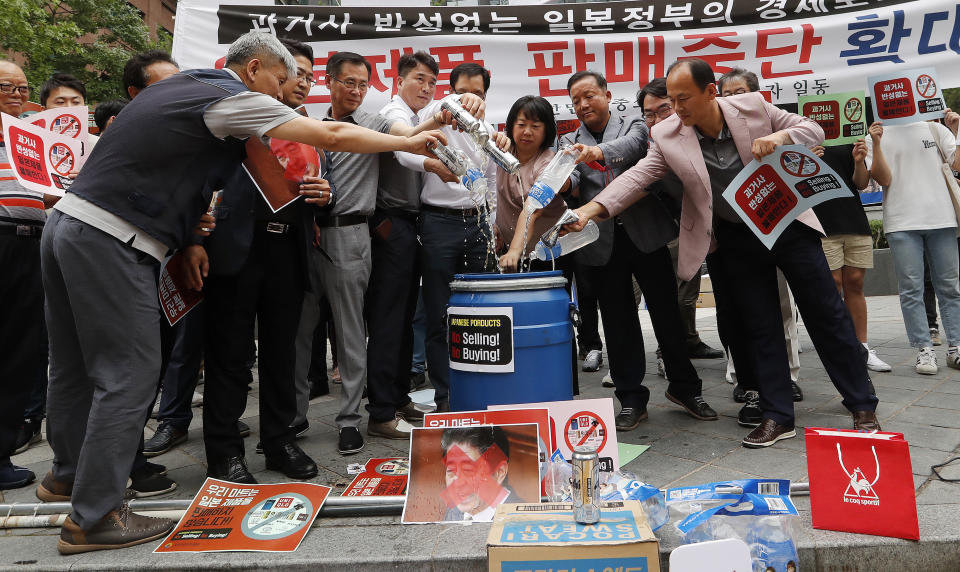 In this July 15 2019, photo, South Korean small and medium-sized business owners pour beers and drinking waters from Japanese brands into a trash can during a rally calling for a boycott of Japanese products in front of the Japanese embassy in Seoul, South Korea, The signs read: "Our supermarket does not sell Japanese products." A widespread anti-Japanese boycott has gained ground in South Korea since Tokyo tightened its exports of materials used to manufacture semiconductors and display screens, key export items for South Korea.(AP Photo/Ahn Young-joon)