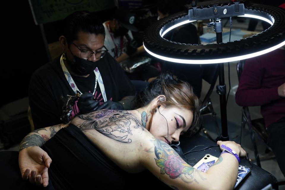 Un tatuador trabaja en la espalda de una mujer durante una convención del sector en el World Trade Center de la Ciudad de México, el 20 de agosto de 2023. Tatuadores de Costa Rica, México, Brasil, Estados Unidos y Colombia se reunieron durante dos días en México. (AP Foto/Arnulfo Franco)