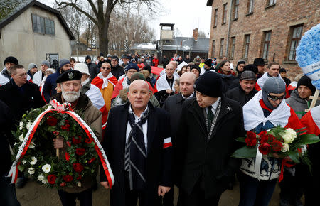 Far right activists walk past the "Arbeit Macht Frei" gate at the former Nazi German concentration and extermination camp Auschwitz, to pay tribute to Polish victims at the "death wall", during the ceremonies marking the 74th anniversary of the liberation of the camp and International Holocaust Victims Remembrance Day, in Oswiecim, Poland, January 27, 2019. REUTERS/Kacper Pempel