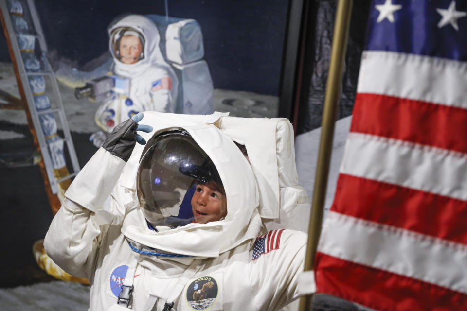 Visitors pose for photos beside a portrait of Neil Armstrong at the Armstrong Air and Space Museum as special events are underway for visitors commemorating the 50th anniversary of the first moon landing, Saturday, July 20, 2019, in Wapakoneta, Ohio. (AP Photo/John Minchillo)