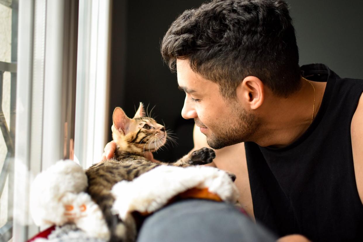 man holding cat on couch