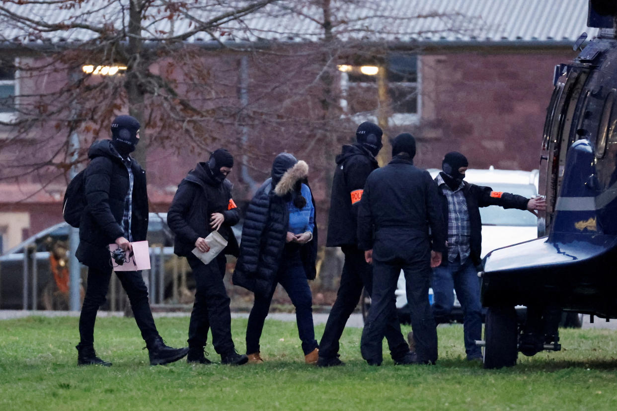 Police escort a person after 25 suspected members and supporters of a far-right group were detained during raids across Germany.