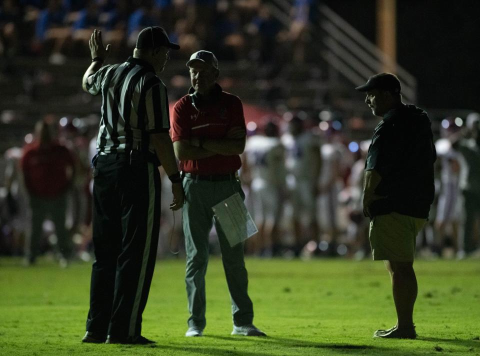 From right, Jaguars head coach Harry Lees, Patriots head coach Kent Smith and a referee confer at mid field after the lights unexpectedly went out on the Jaguars side of the field during the Pace vs West Florida football game at West Florida High School in Pensacola on Friday, Sept. 8, 2023.