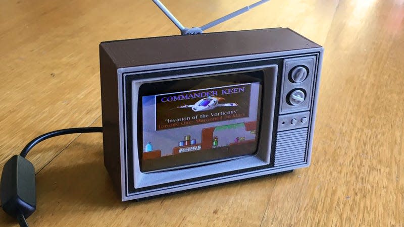 A tiny 3D-printed Toshiba TV with a modern LCD screen playing Commander Keen on a wooden table.