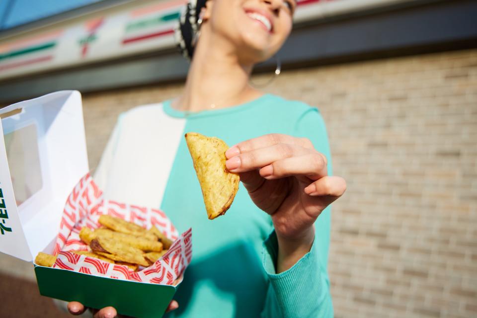 A smiling 7-Eleven customer holds mini tacos.