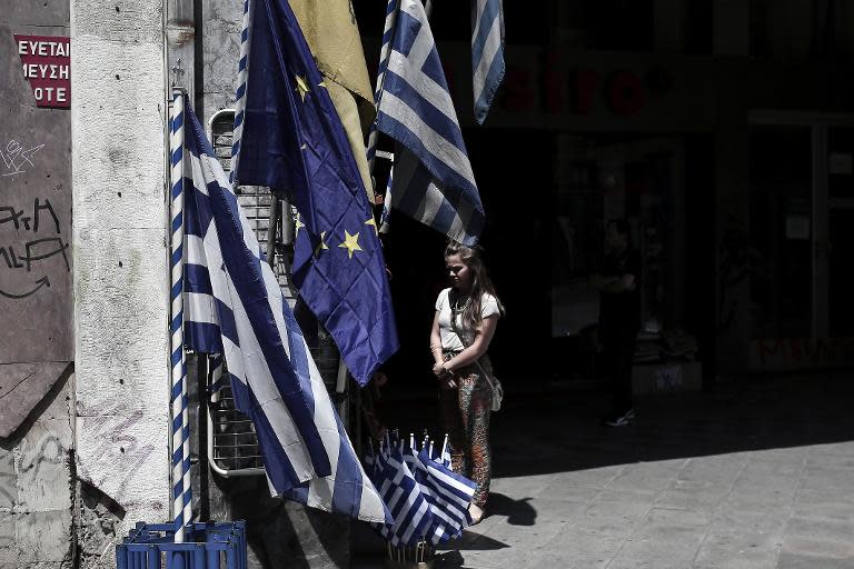 A woman stands next to flags of the European Union and Greece on May 17, 2015 in Athens