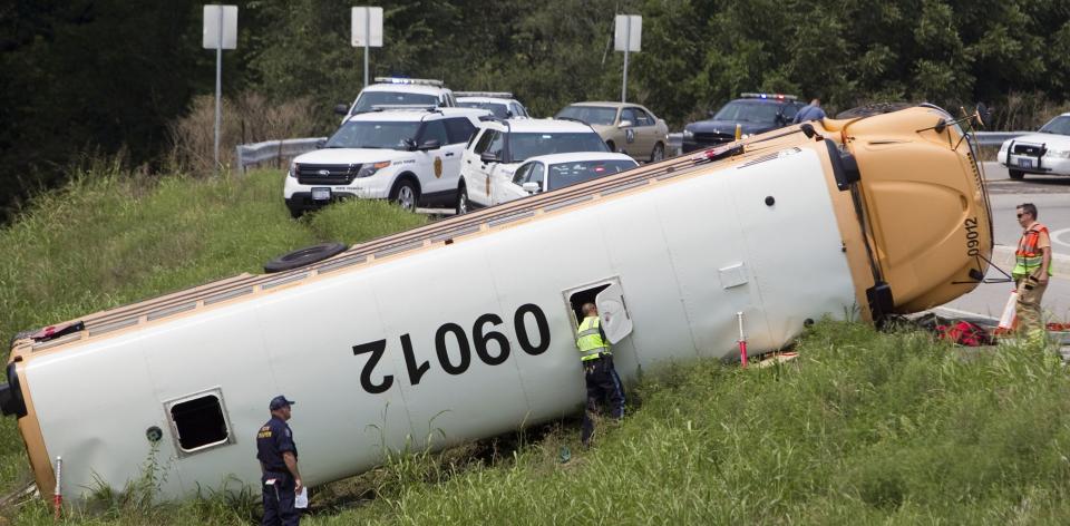 Rescue crews and law enforcement workers continue their investigation of a school bus that overturned while transporting girls from Pembroke Hill School to a campout Wednesday, August 21, 2013, in Bonner Springs, Kansas. Several students were transported to area hospitals, but no one was killed in the accident. 