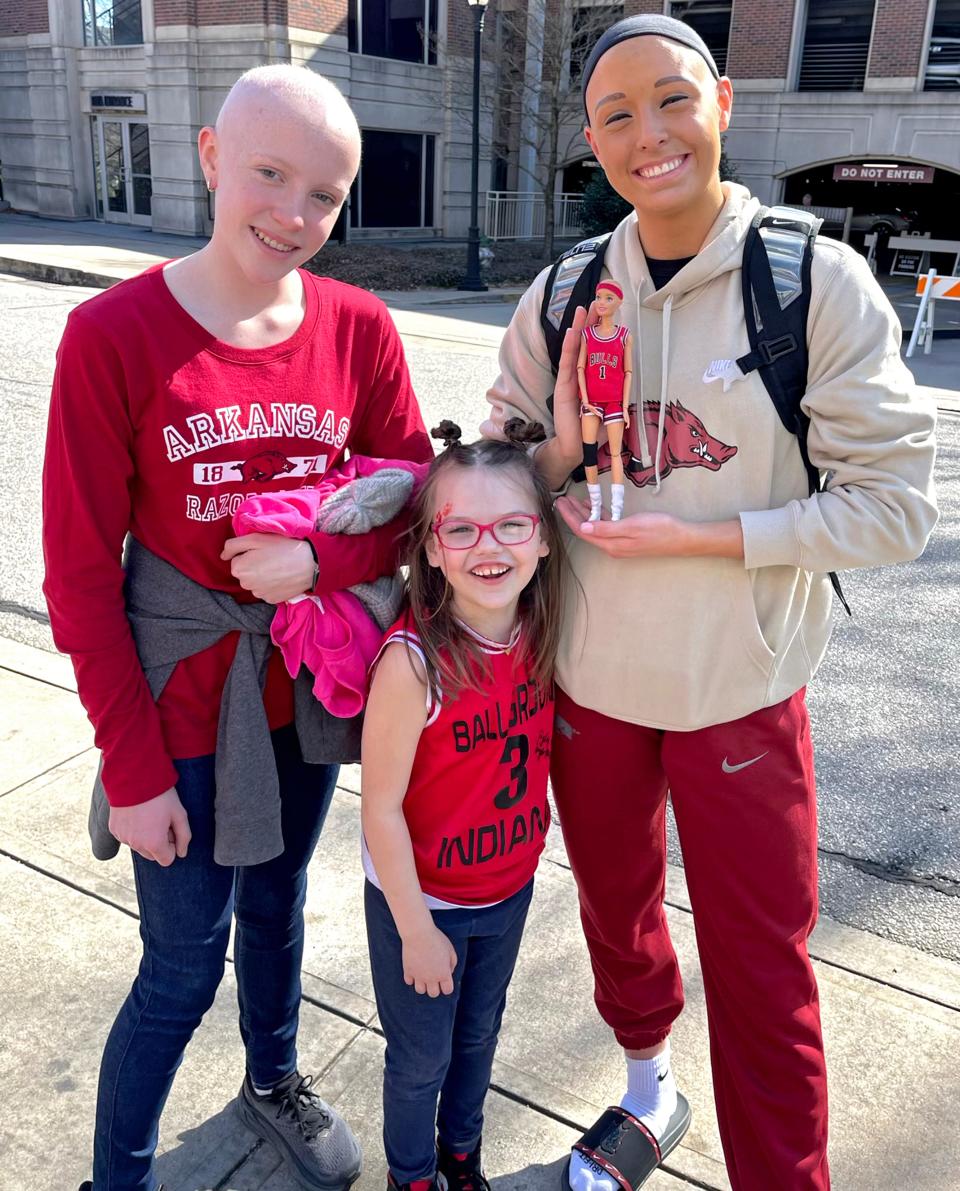 Rylee Langerman poses with two young fans as a player at Arkansas. Langerman, now at Oklahoma State, has alopecia and has become a role model for others dealing with the disorder.