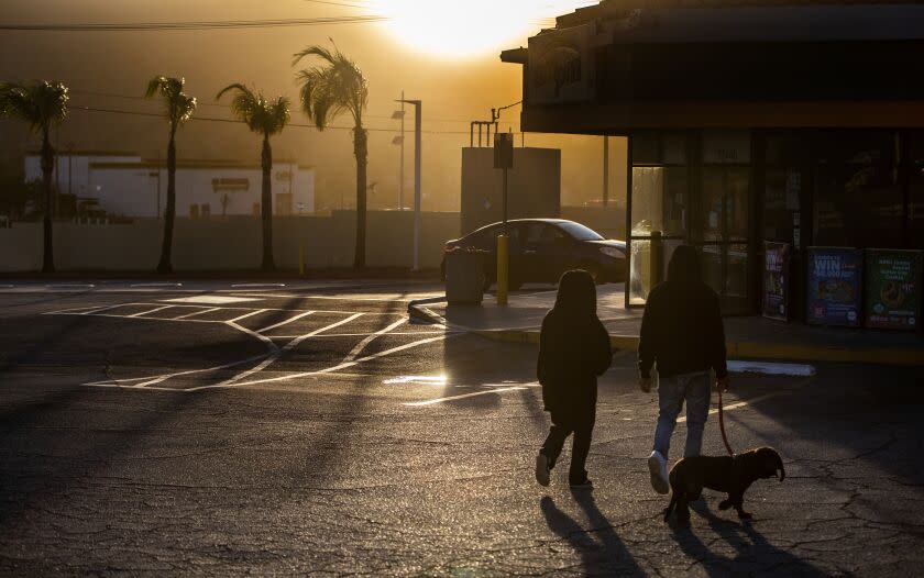 SAN JACINTO, CA - NOVEMBER 24, 2022: Residents walk to a darkened mini mart after powerful winds forced Southern California Edison to shut off the power to the area on Thanksgiving day November 24, 2022 in San Jacinto, California. The power is out in the area of Highway 74 and Vista Place. The San Ana winds will continue through Friday.(Gina Ferazzi / Los Angeles Times)