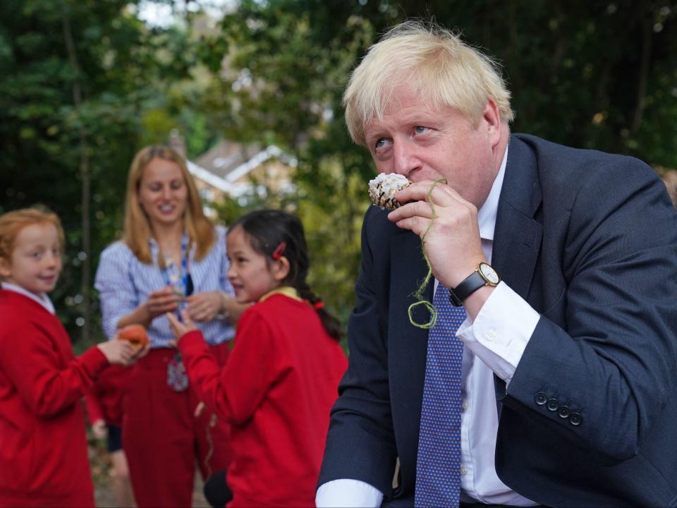 Johnson smells a bird feeder he made with the children (PA)