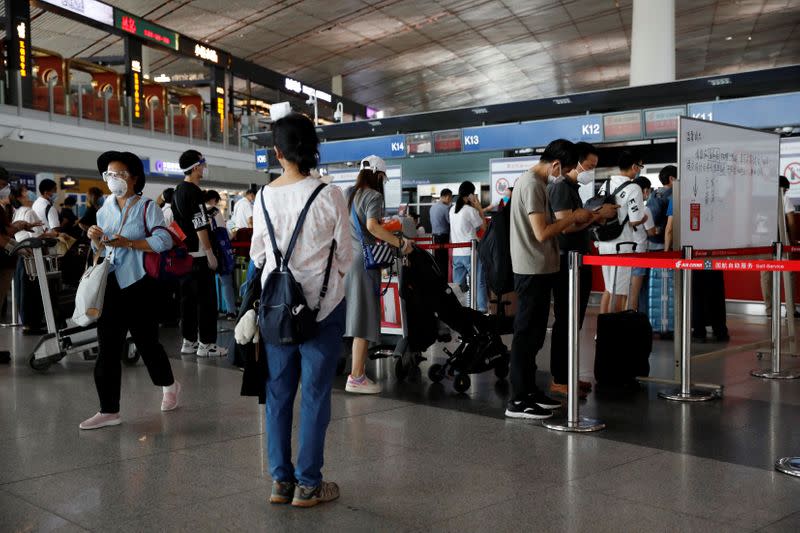 People wearing protective gear line up at Beijing Capital International Airport