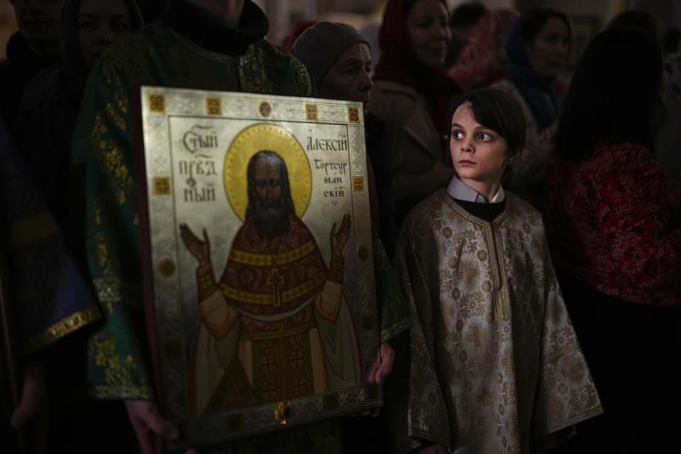 A young parishioner prepares to take part in a religion procession during the Orthodox Easter service at the Church of the Holy Martyr Tatiana just next to the Kremlin Wali in Moscow, Russia, Saturday, April 15, 2023. (AP Photo/Alexander Zemlianichenko)