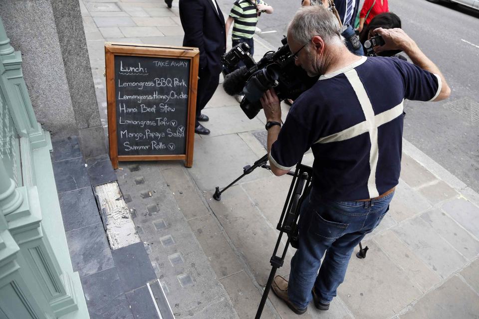 A camera man films broken slates outside a cafe in London