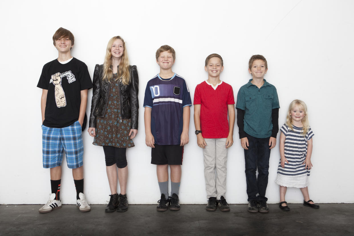 indoors, studio, front lit, copy space, horizontal, full length, full frame, group of kids, 10-11 years, 6-8 years, toddler, blonde hair, brown hair stripes, red, blue, shorts, kids only, height, boys, girls, teenager, pre-teens, smiling, happy, silly, leather jacket, tee shirt, jersey, stripes, gym shorts, khakis, jeans, socks, tennis shoes