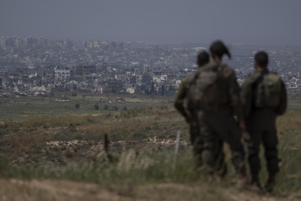 Israeli soldiers look at destroyed buildings in the Gaza Strip as they stand near the Israeli-Gaza border, as seen from southern Israel, Tuesday, April 9, 2024. (AP Photo/Leo Correa)