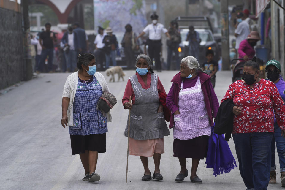 Women walk on the ash-covered streets from the Popocatepetl volcano in Santiago Xalitzintla, Mexico, Monday, May 22, 2023. The volcano´s activity has increased over the past week. Evacuations have not been ordered, but authorities are preparing for that scenario and telling people to stay out of 7.5-mile (12-kilometer) radius around the peak. (AP Photo/Marco Ugarte)