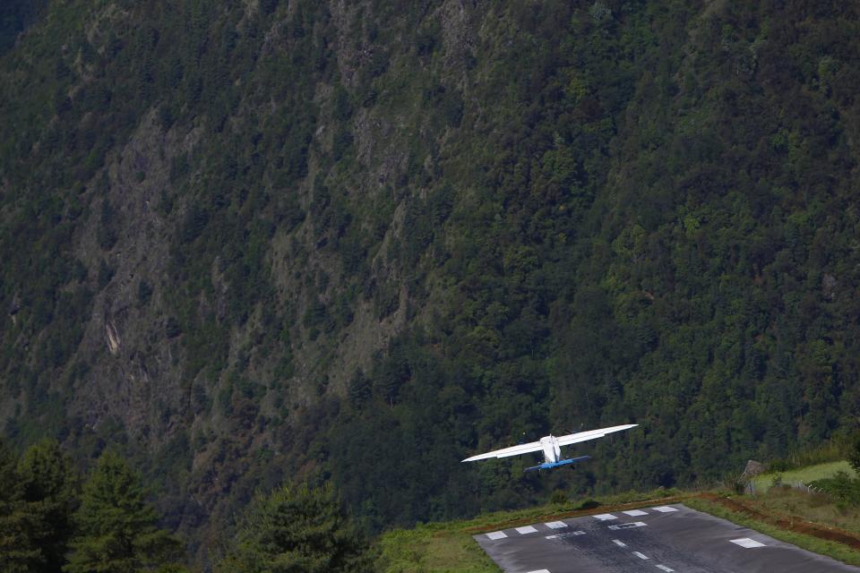 In this Sunday, May 26, 2013 photo, a flight takes off for Katmandu from Lukla airport, Nepal. Carved out of side of a mountain, the airport was built by Sir Edmund Hillary in 1965, and at an altitude of 2,843 meters (9,325 feet) the Lukla airport has earned the reputation of being one of the most extreme and dangerous airports in the world. (AP Photo/Niranjan Shrestha)