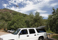 <p>A Department of Public Safety helicopter hovers over as a mortuary vehicle awaits for victims on the parking lot of Water Well Campground in the Tonto National Forest, Ariz, Sunday morning, July 16, 2017, following Saturday’s deadly flash-flooding at Cold Springs canyon. (Alexis Bechman/Payson Roundup via AP) </p>