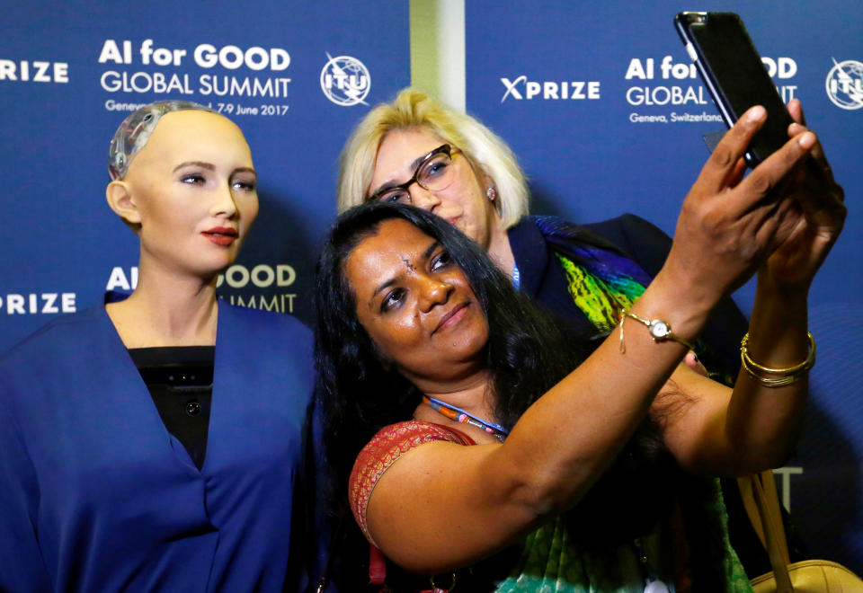 Attendees pose with Sophia, a robot integrating the latest technologies and artificial intelligence developed by Hanson Robotics during a presentation at the "AI for Good" Global Summit at the International Telecommunication Union (ITU) in Geneva, Switzerland June 7, 2017. REUTERS/Denis Balibouse