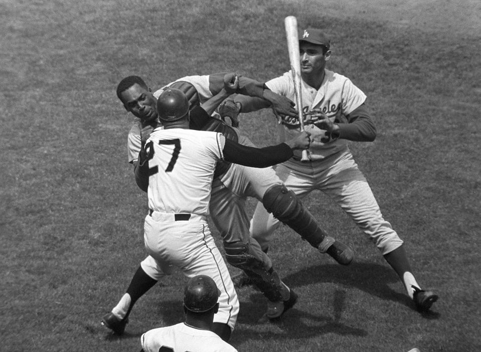 FILE - In this Aug. 22, 1965, file photo, San Francisco Giants pitcher Juan Marichal (27) swings a bat at Los Angeles Dodgers catcher John Roseboro as Dodgers pitcher Sandy Koufax, rear right, tries to break it up in the third inning at Candlestick Park in San Francisco. Violence is part of the game in many sports. But when the Cleveland’s Myles Garrett ripped the helmet off Mason Rudolph and hit the Pittsburgh Steelers’ quarterback in the head with it, the Browns’ defender crossed a line _ one that attracts the attention of authorities sometimes from within their sport and in other cases from criminal prosecutors. (AP Photo/Robert H. Houston, File)