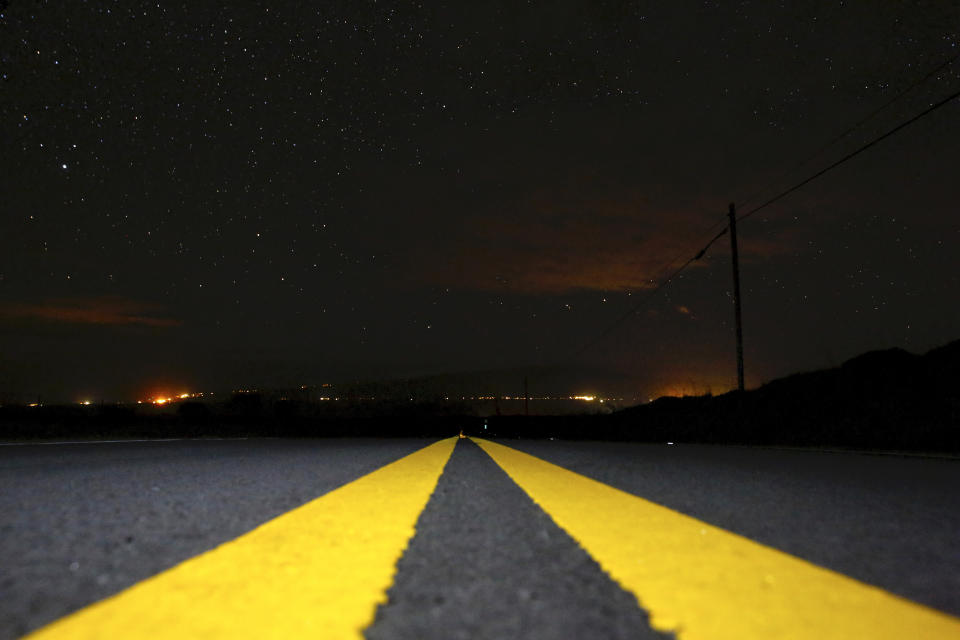 Lights from Waimea, Hawaii, shine in the distance as wildfires burn in the area on Thursday, Aug. 5, 2021. The region was scorched by the state's largest-ever wildfire. (AP Photo/Caleb Jones)