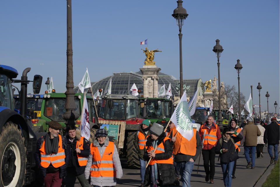 Farmers carry union flags in front of the Grand Palais museum on the Esplanade des Invalides,, Wednesday, Feb. 8, 2023 in Paris. French sugarbeet and other farmers disrupt Paris traffic with hundreds of tractors to protest an EU pesticide ban they say will devastate their livelihoods and industry. (AP Photo/Christophe Ena)