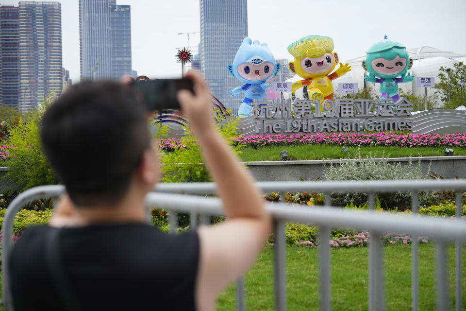 A man uses his mobile phone to take pictures outside Hangzhou Olympic Sports Centre Stadium ahead of the 19th Asian Games in Hangzhou, China, Wednesday, Sept. 20, 2023. The Asian Games are an attention grabber. For starters, they involve more participants than the Summer Olympics. Organizers say more than 12,000 will be entered as the opening ceremony takes place Saturday, Sept. 23 in the eastern Chinese city of Hangzhou. (AP Photo/Vincent Thian)