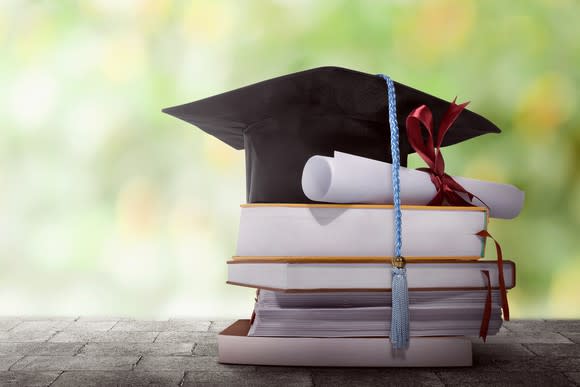 College graduation cap and degree sitting atop a pile of books.