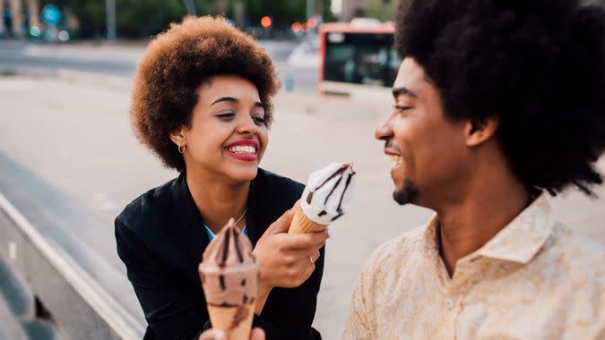 Beautiful African - American girl sharing the ice cream with her boyfriend.