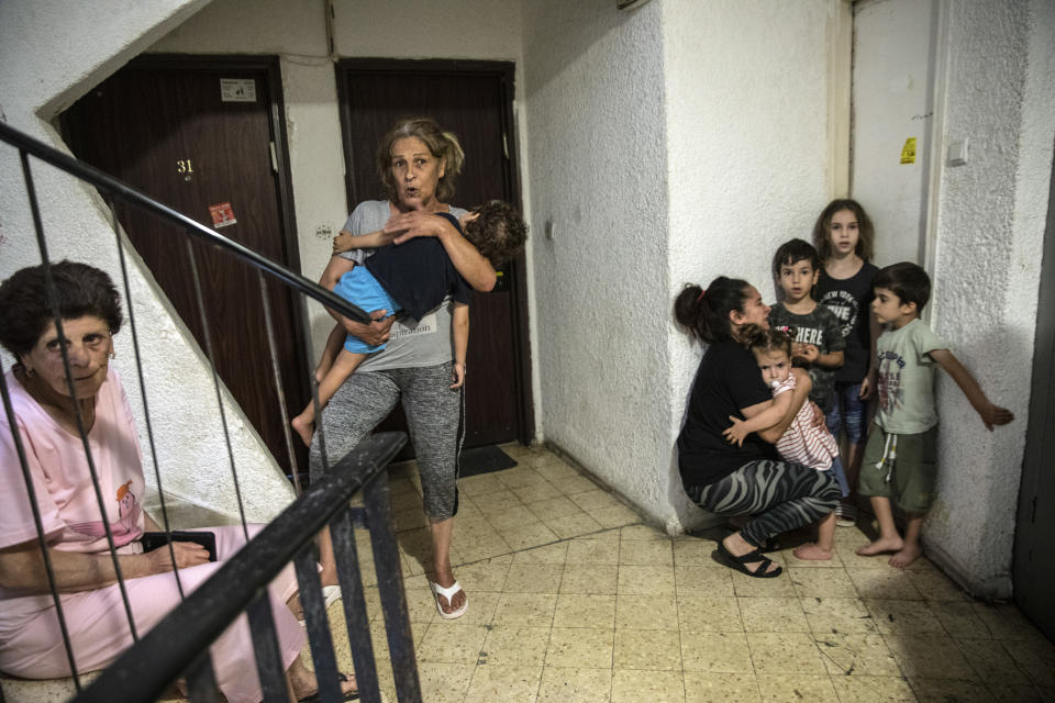 Israelis take shelter in the stairwell of their apartment building as a siren sounds a warning of incoming rockets fired from the Gaza Strip, In Ashdod, Israel, Thursday, May 20, 2021. (AP Photo/Heidi Levine)